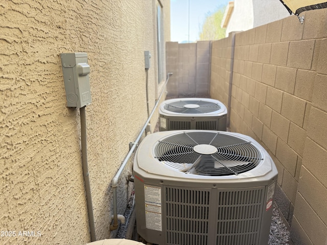 exterior details featuring fence, central AC unit, and stucco siding