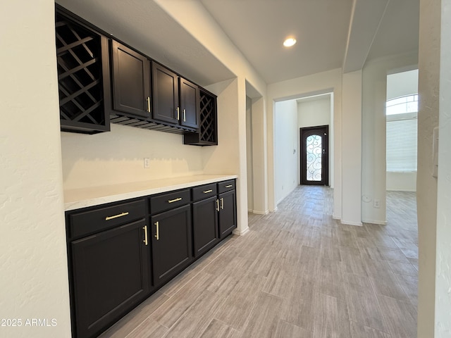 bar featuring a dry bar, light wood-style flooring, and baseboards