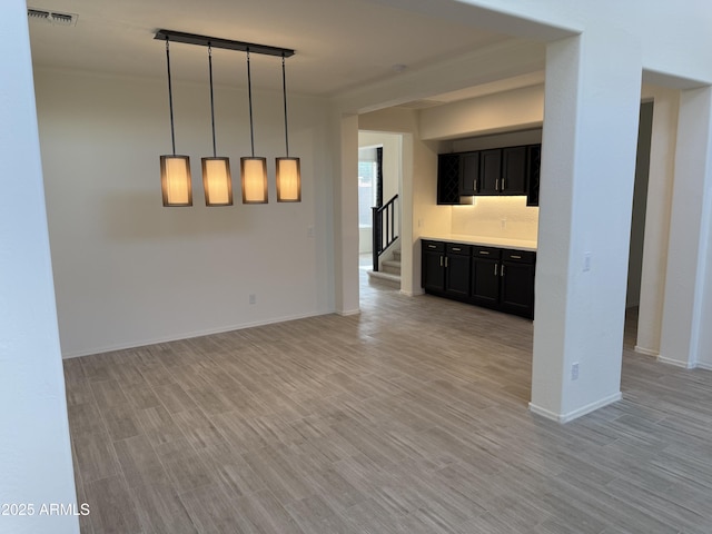 unfurnished living room featuring light wood-style flooring, stairway, visible vents, and baseboards