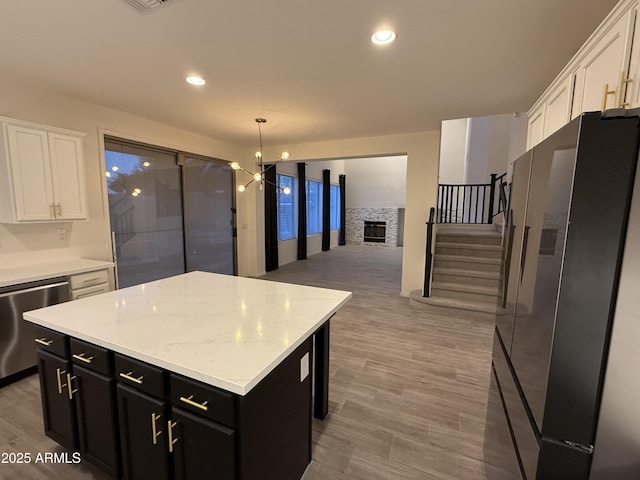 kitchen with a center island, freestanding refrigerator, white cabinetry, dark cabinetry, and dishwasher