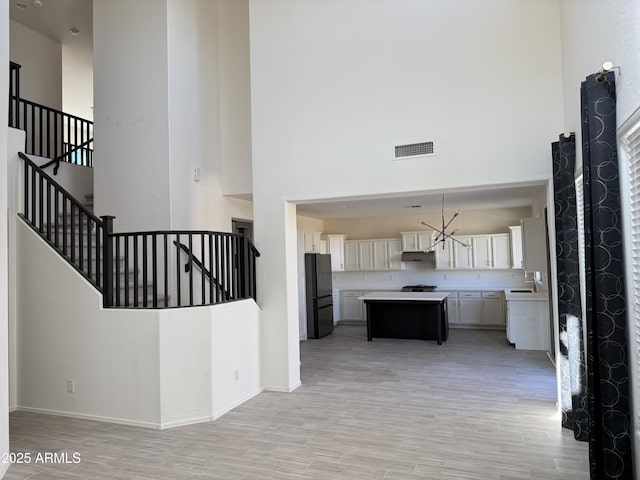 kitchen featuring a center island, light countertops, visible vents, freestanding refrigerator, and open floor plan