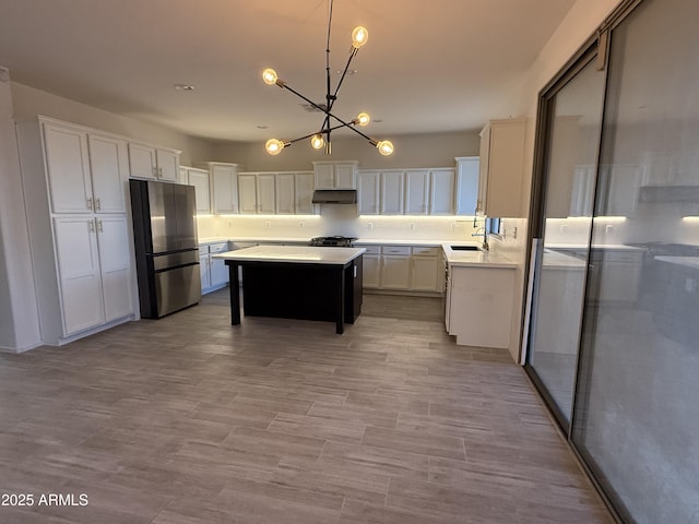 kitchen featuring a kitchen island, light countertops, decorative light fixtures, and freestanding refrigerator