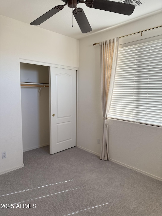 unfurnished bedroom with carpet, baseboards, ceiling fan, and a closet