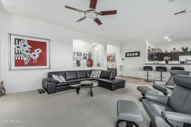582 W Stirrup Ln, San Tan Valley, AZ 85143 - living room with arched walkways, baseboards, visible vents, light colored carpet, and a ceiling fan