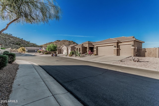 582 W Stirrup Ln, San Tan Valley, AZ 85143 - view of front facade with a tile roof, concrete driveway, fence, an attached garage, and stucco siding