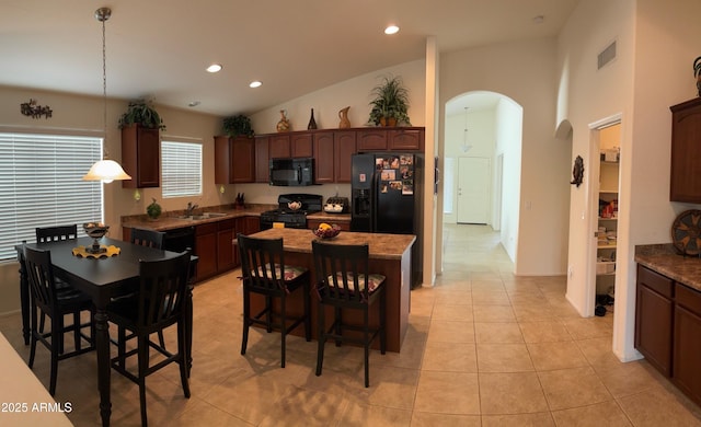 kitchen with light tile patterned floors, visible vents, arched walkways, black appliances, and a sink