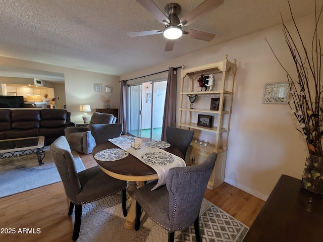 dining room featuring hardwood / wood-style floors, ceiling fan, and a textured ceiling