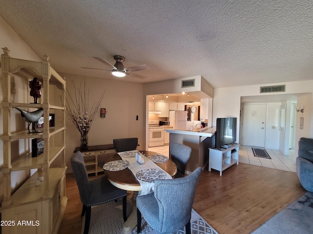 dining space with a textured ceiling, light hardwood / wood-style flooring, and ceiling fan