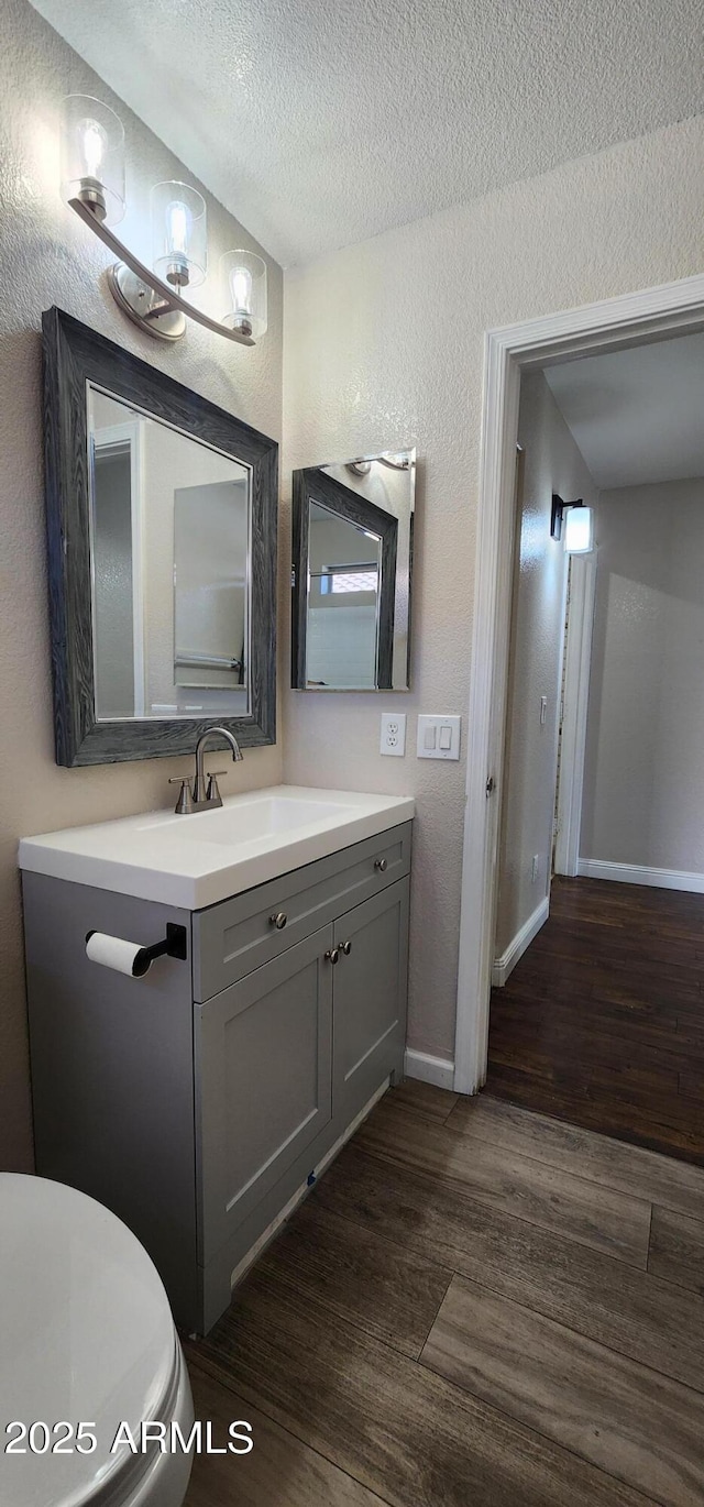 bathroom with toilet, wood-type flooring, vanity, and a textured ceiling