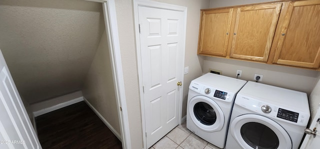 laundry room with cabinets, washing machine and dryer, and light tile patterned floors