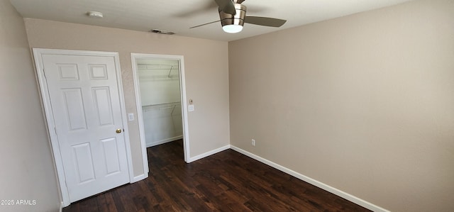 unfurnished bedroom with dark hardwood / wood-style flooring, ceiling fan, a closet, and a spacious closet