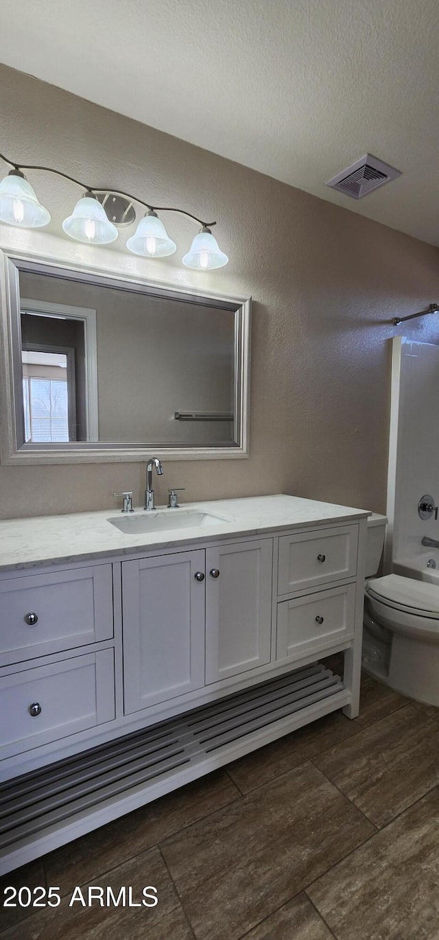 full bathroom featuring bathtub / shower combination, toilet, a textured ceiling, vanity, and hardwood / wood-style floors