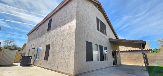 view of side of home with central AC unit and a patio