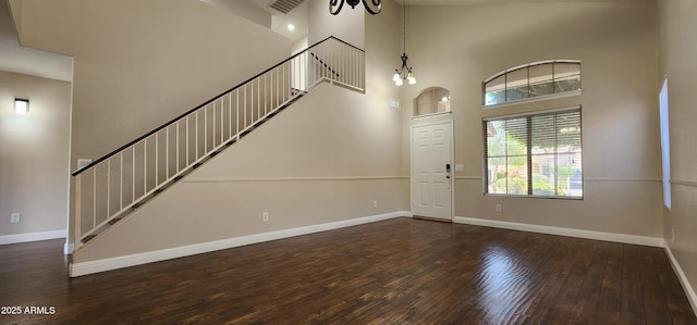 entryway with an inviting chandelier, dark wood-type flooring, and a high ceiling