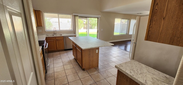 kitchen with appliances with stainless steel finishes, light tile patterned floors, sink, and a center island