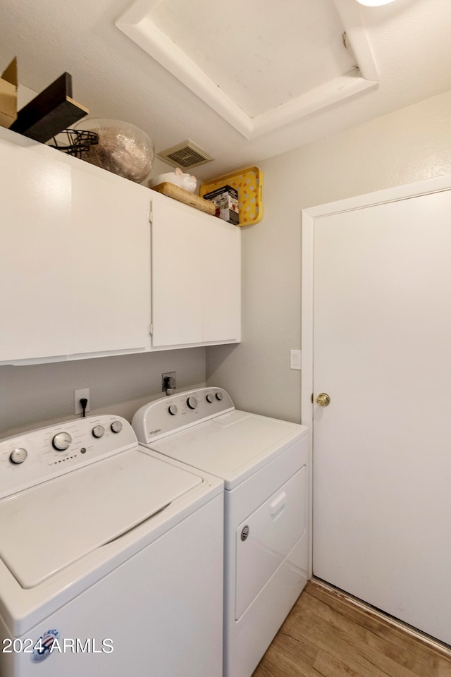 laundry room featuring cabinets, light hardwood / wood-style floors, and washing machine and dryer