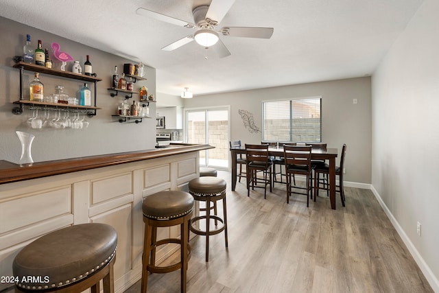 bar with light hardwood / wood-style floors and ceiling fan