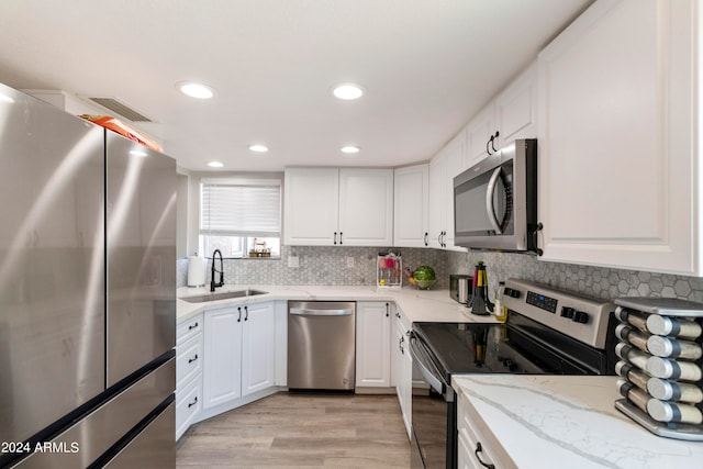 kitchen featuring light stone counters, white cabinets, sink, appliances with stainless steel finishes, and light wood-type flooring