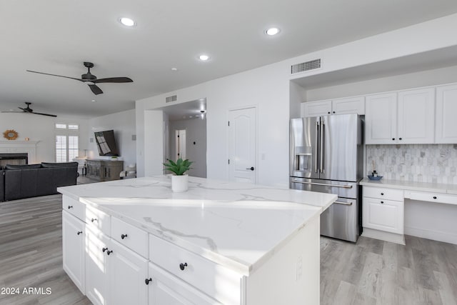 kitchen featuring light wood-type flooring, white cabinets, stainless steel fridge, and a kitchen island