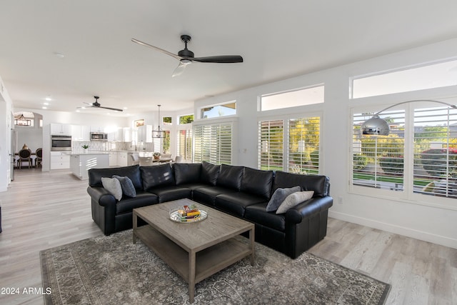 living room featuring ceiling fan, light hardwood / wood-style floors, and a wealth of natural light