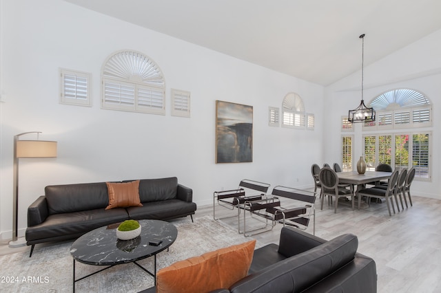 living room featuring high vaulted ceiling, a chandelier, and wood-type flooring