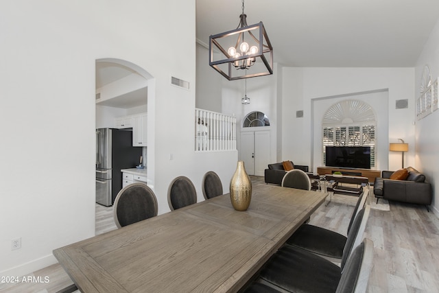 dining area featuring high vaulted ceiling, light hardwood / wood-style flooring, and an inviting chandelier