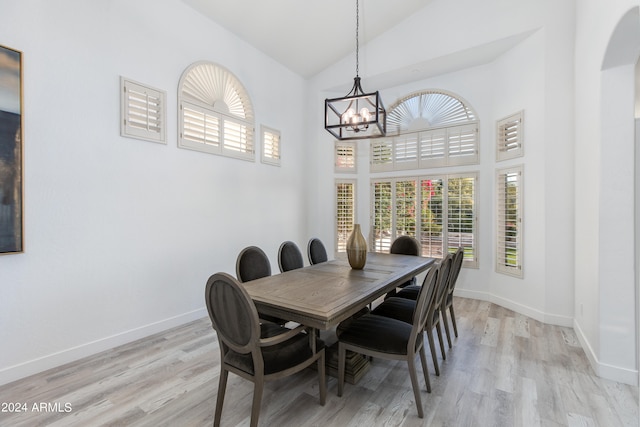 dining area with high vaulted ceiling, light hardwood / wood-style floors, and a notable chandelier