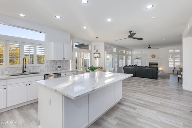 kitchen with light hardwood / wood-style flooring, tasteful backsplash, white cabinetry, a center island, and sink