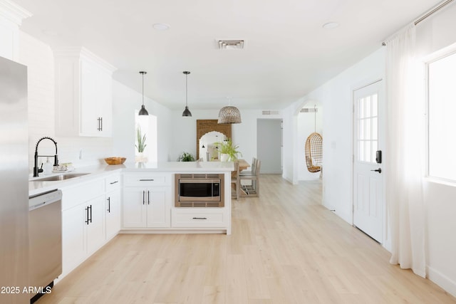 kitchen with stainless steel appliances, kitchen peninsula, sink, and white cabinets