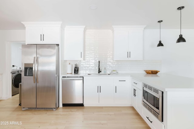 kitchen with stainless steel appliances, washer / dryer, and white cabinets