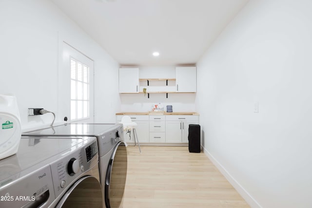 laundry area with cabinets, independent washer and dryer, and light hardwood / wood-style floors