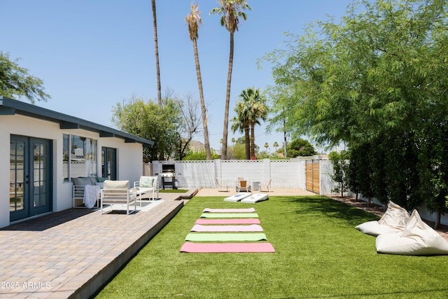 view of yard with an outdoor living space, a patio area, and french doors