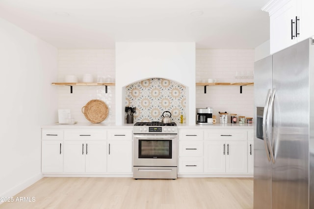 kitchen with appliances with stainless steel finishes, white cabinets, and light hardwood / wood-style flooring