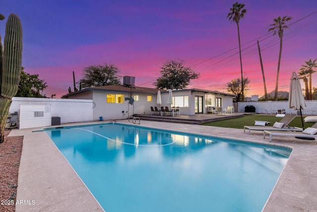 pool at dusk featuring central AC unit and a patio