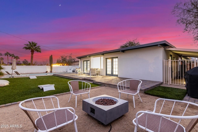 patio terrace at dusk with french doors, an outdoor fire pit, and a grill