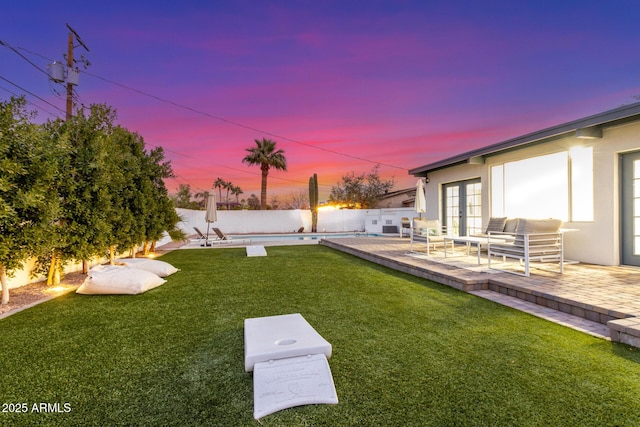 yard at dusk with a patio, a swimming pool, an outdoor hangout area, and french doors