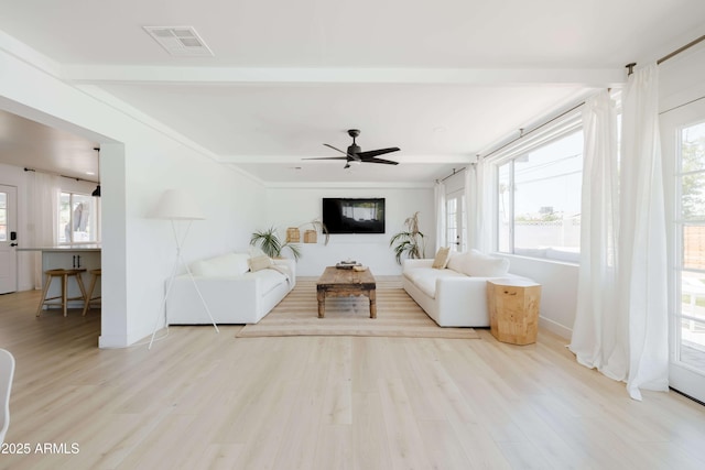 unfurnished living room featuring beamed ceiling, ceiling fan, and light wood-type flooring