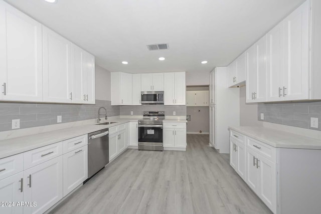 kitchen featuring white cabinetry, sink, stainless steel appliances, and light hardwood / wood-style flooring