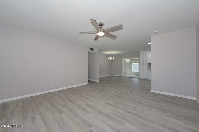 unfurnished room with ceiling fan with notable chandelier and light hardwood / wood-style flooring