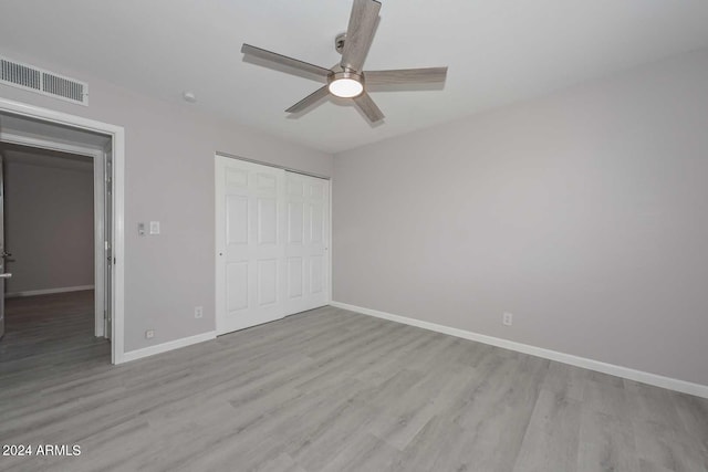 unfurnished bedroom featuring ceiling fan, light hardwood / wood-style floors, and a closet