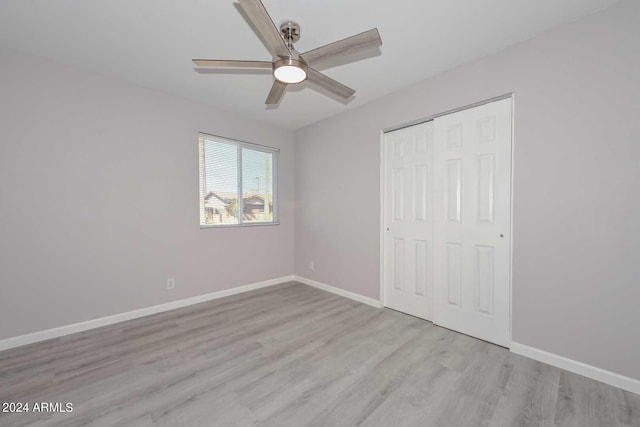 unfurnished bedroom with ceiling fan, a closet, and light wood-type flooring