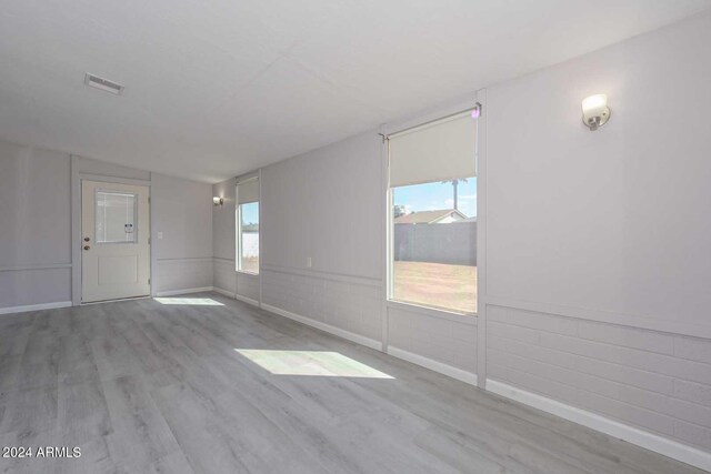 spare room featuring light hardwood / wood-style floors and lofted ceiling