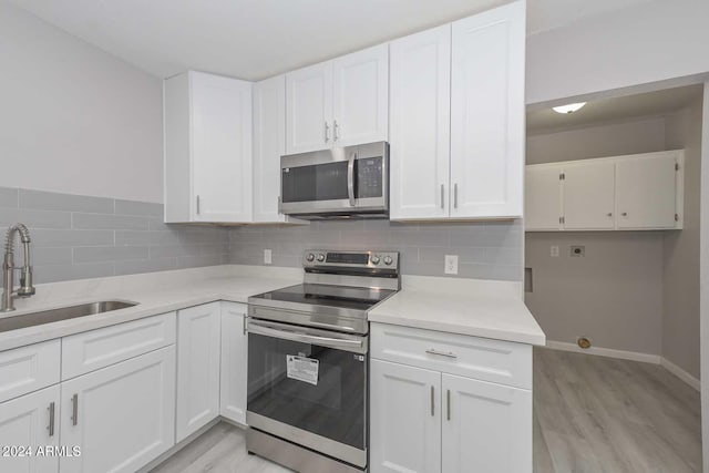 kitchen with white cabinets, sink, stainless steel appliances, and tasteful backsplash