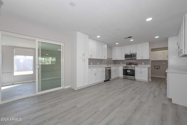 kitchen with sink, light wood-type flooring, white cabinetry, and stainless steel appliances