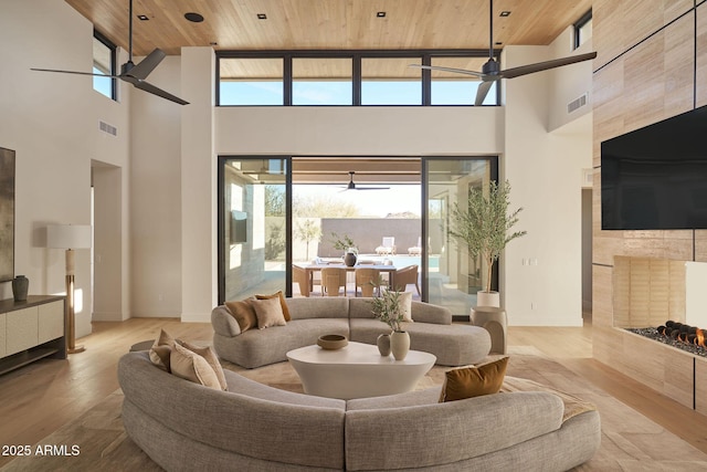 living room with a towering ceiling, wooden ceiling, and light wood-type flooring