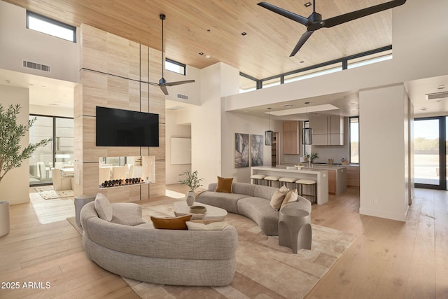 living room featuring ceiling fan, wooden ceiling, and a high ceiling