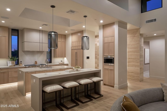 kitchen featuring a kitchen island, light brown cabinetry, light hardwood / wood-style flooring, and pendant lighting