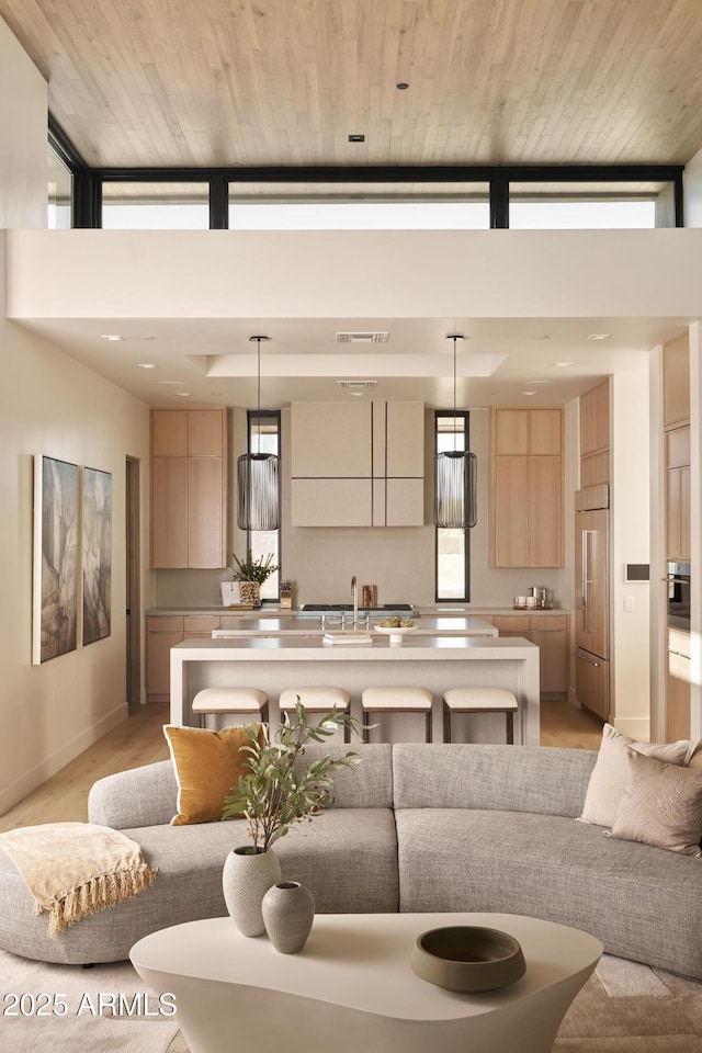 living room featuring a towering ceiling, sink, and wood ceiling