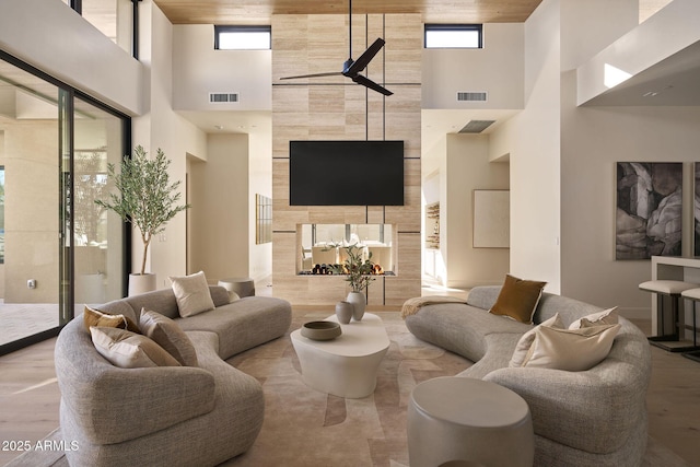 living room with wood ceiling, a towering ceiling, and plenty of natural light