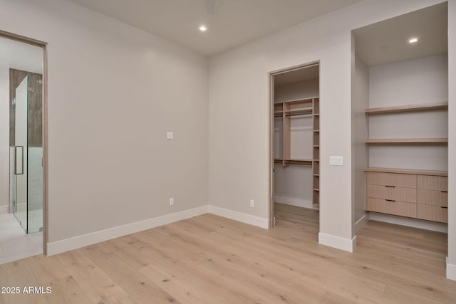 unfurnished bedroom featuring a spacious closet, a closet, and light wood-type flooring